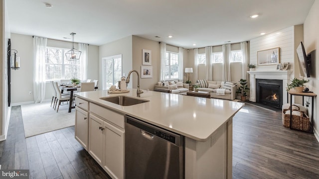 kitchen featuring sink, stainless steel dishwasher, an island with sink, decorative light fixtures, and white cabinetry