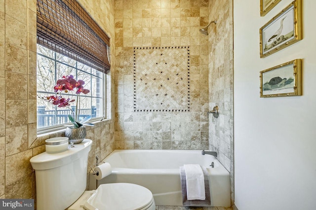 bathroom featuring toilet, tiled shower / bath combo, and tile walls