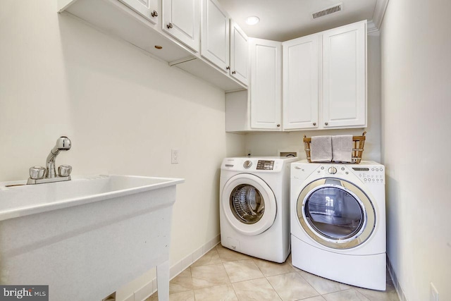 clothes washing area with washer and clothes dryer, cabinets, and light tile patterned floors