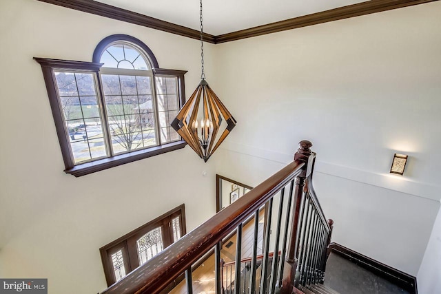 staircase with ornamental molding and a chandelier