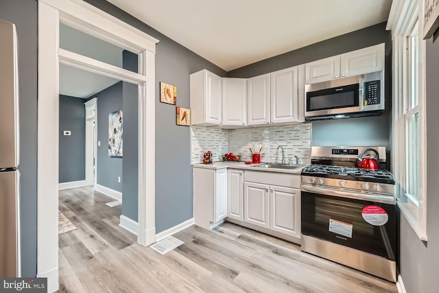 kitchen with white cabinets, appliances with stainless steel finishes, decorative backsplash, and sink