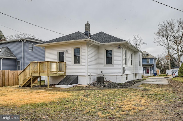 back of property with a lawn, a wooden deck, and central AC unit