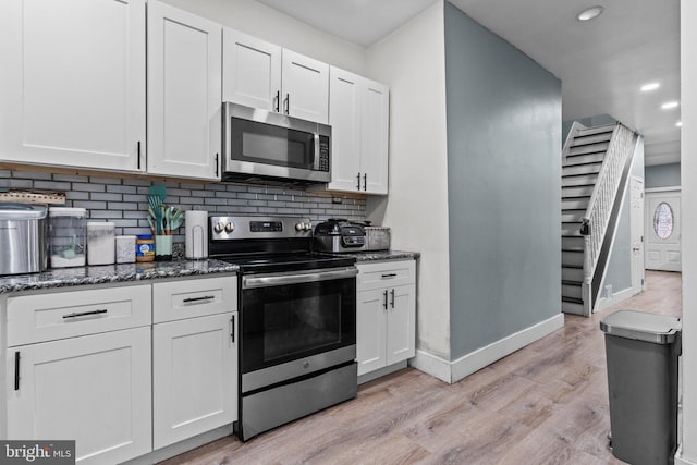 kitchen with white cabinets, light wood-type flooring, stainless steel appliances, and tasteful backsplash