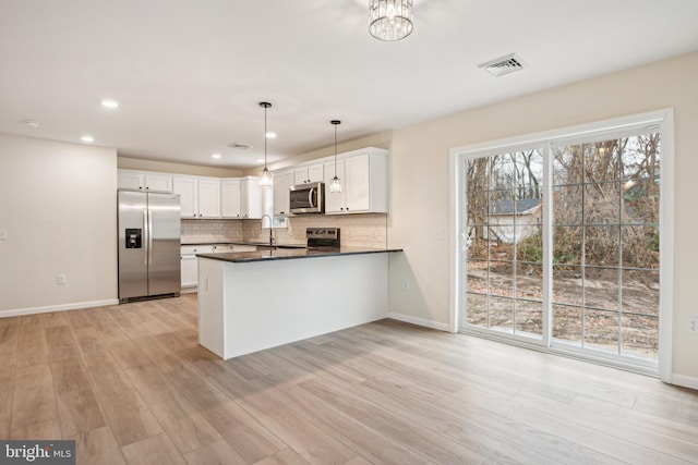 kitchen featuring white cabinets, sink, hanging light fixtures, appliances with stainless steel finishes, and kitchen peninsula