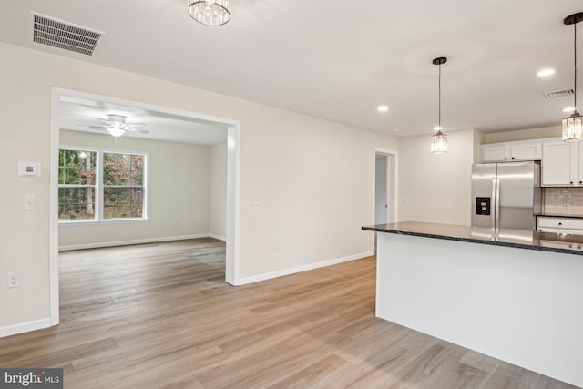 kitchen with pendant lighting, light hardwood / wood-style flooring, stainless steel fridge with ice dispenser, tasteful backsplash, and white cabinetry