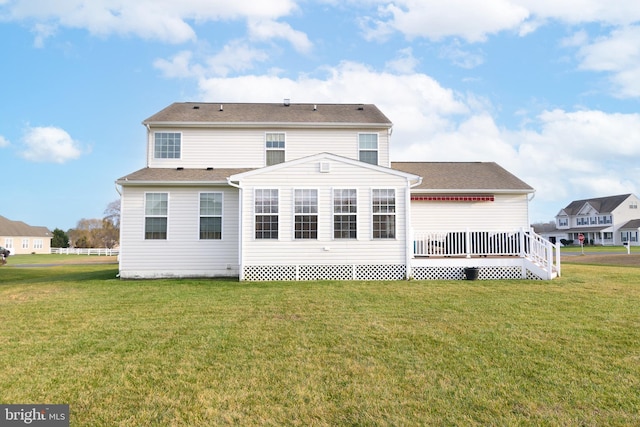 rear view of house featuring a deck and a lawn