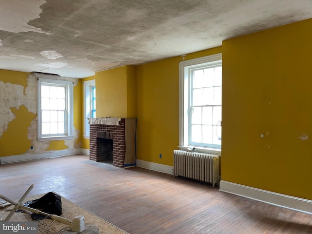 unfurnished living room with hardwood / wood-style floors, plenty of natural light, and radiator