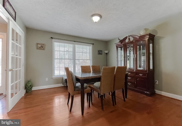 dining room with hardwood / wood-style floors, a textured ceiling, and french doors