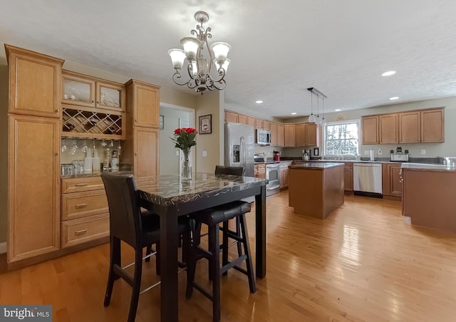 dining area with sink, an inviting chandelier, a textured ceiling, and light wood-type flooring