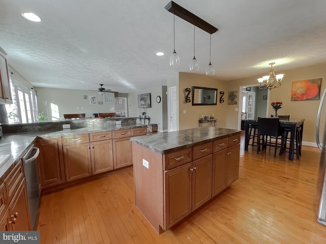 kitchen with dishwasher, a center island, ceiling fan with notable chandelier, decorative light fixtures, and light hardwood / wood-style floors