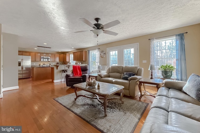 living room with a textured ceiling, light hardwood / wood-style flooring, and a wealth of natural light