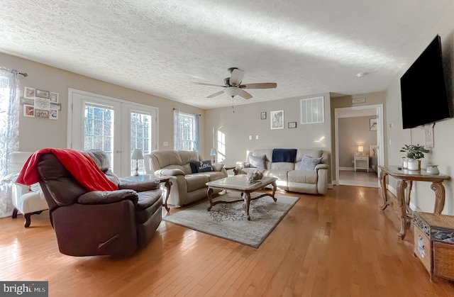 living room featuring hardwood / wood-style floors, ceiling fan, and a textured ceiling