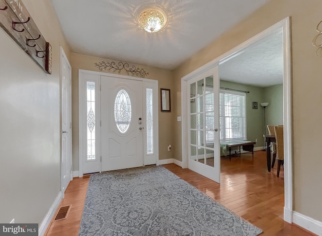 entrance foyer featuring hardwood / wood-style flooring, a textured ceiling, a wealth of natural light, and french doors