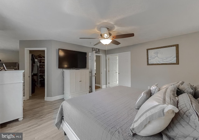 bedroom featuring ceiling fan, light hardwood / wood-style floors, a walk in closet, and a closet