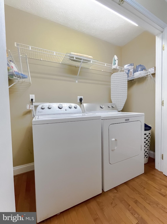 washroom featuring independent washer and dryer, wood-type flooring, and a textured ceiling