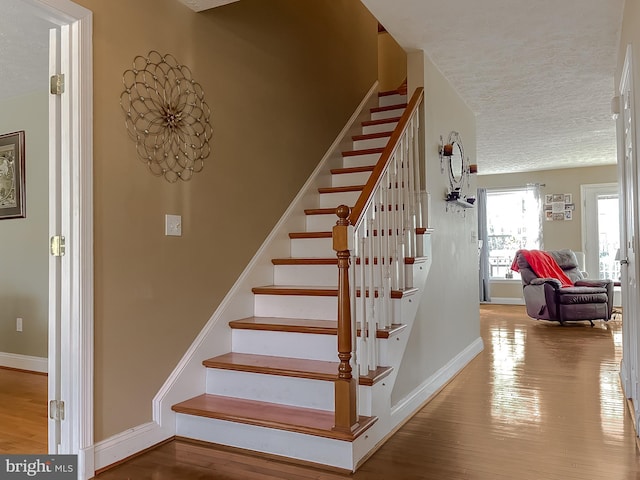 staircase featuring a textured ceiling and hardwood / wood-style flooring