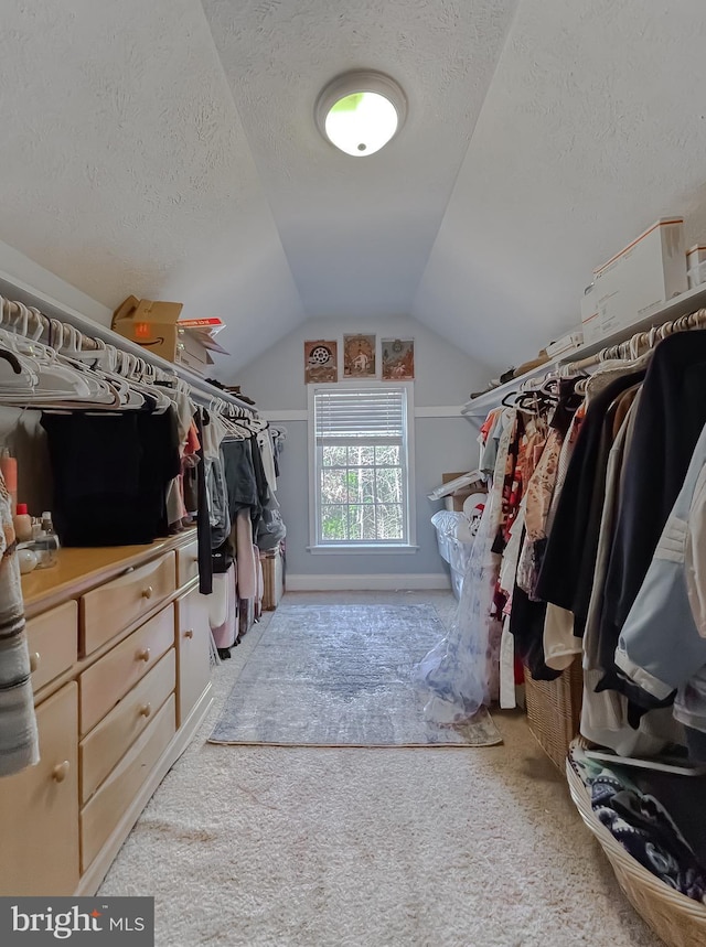 spacious closet featuring light colored carpet and vaulted ceiling