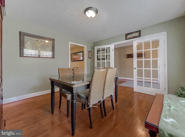 dining room with french doors, a textured ceiling, and hardwood / wood-style flooring