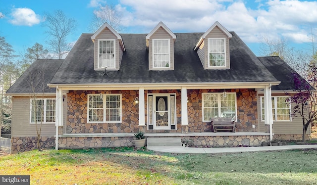 cape cod home featuring covered porch and a front yard