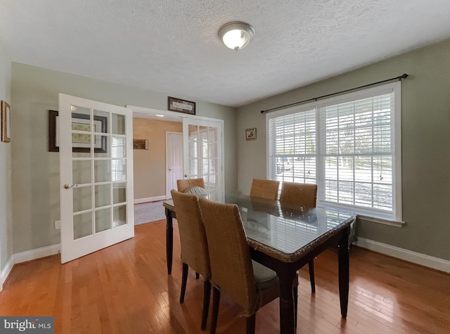 dining area with hardwood / wood-style floors, a textured ceiling, and french doors