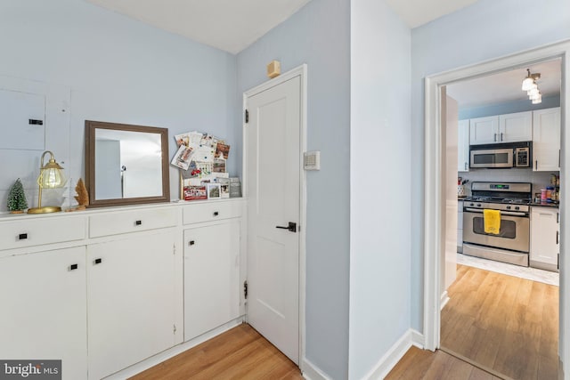 kitchen with appliances with stainless steel finishes, light hardwood / wood-style flooring, white cabinetry, and decorative light fixtures