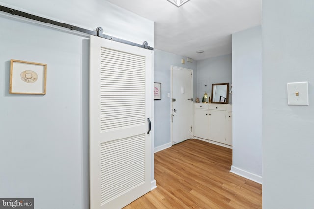 hallway featuring a barn door and light hardwood / wood-style floors