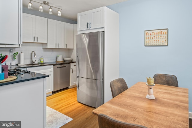 kitchen with tasteful backsplash, sink, white cabinets, and appliances with stainless steel finishes