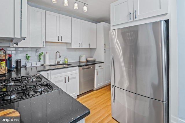 kitchen with backsplash, light wood-type flooring, stainless steel appliances, sink, and white cabinetry