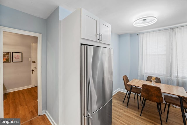 kitchen with white cabinets, light wood-type flooring, and stainless steel refrigerator