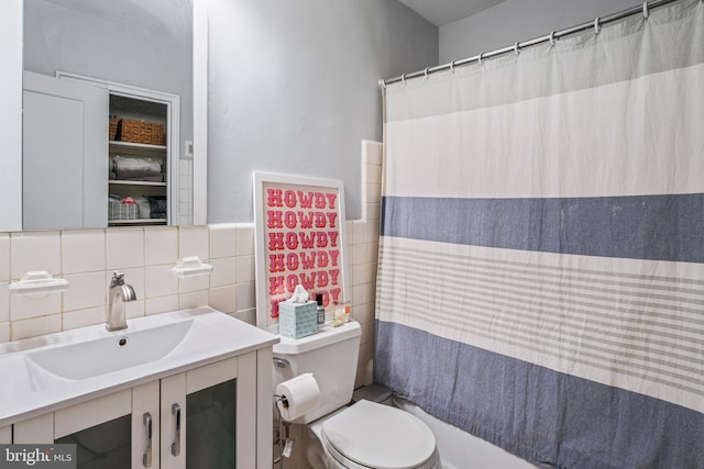 bathroom with vanity, toilet, tile walls, and walk in shower