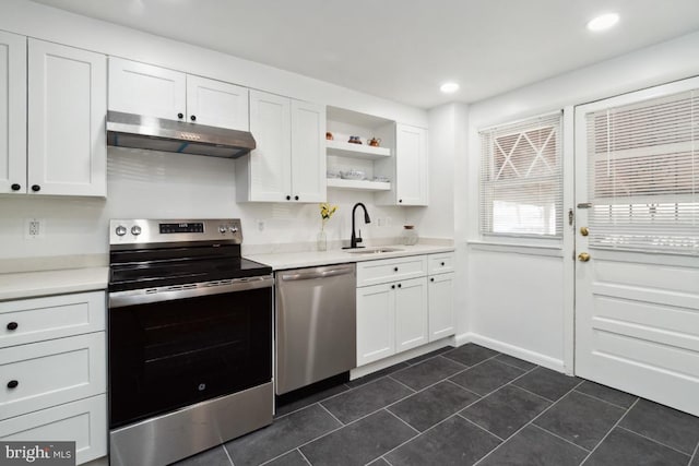 kitchen featuring stainless steel appliances, sink, white cabinets, and dark tile patterned flooring