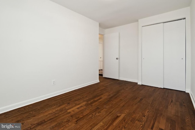 unfurnished bedroom with dark hardwood / wood-style flooring and a closet