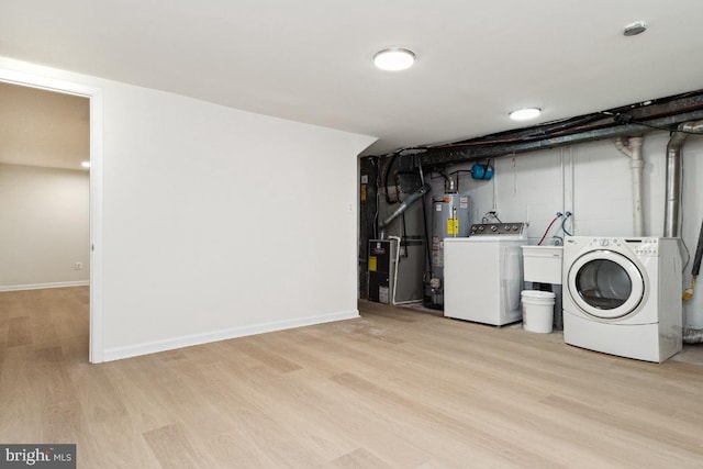 laundry room with sink, heating unit, light wood-type flooring, washer and clothes dryer, and water heater