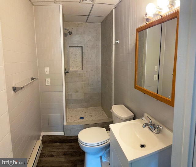 bathroom featuring vanity, tiled shower, hardwood / wood-style flooring, a baseboard radiator, and toilet