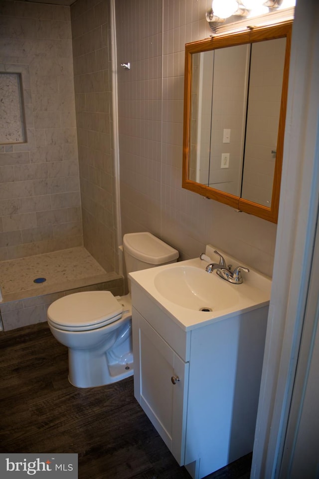 bathroom featuring tiled shower, toilet, vanity, tile walls, and hardwood / wood-style flooring