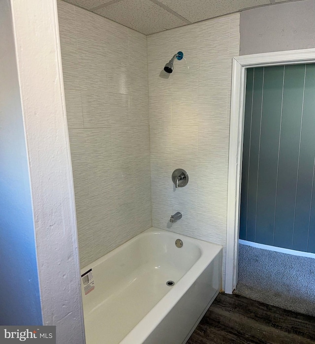 bathroom featuring shower / washtub combination, a drop ceiling, and hardwood / wood-style flooring