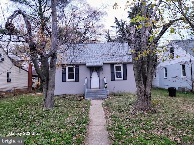 view of front of property with central air condition unit and a front lawn