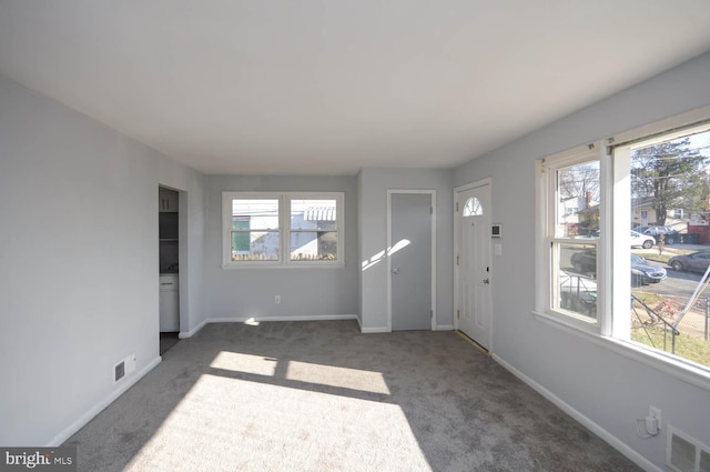 foyer entrance with a wealth of natural light and dark carpet