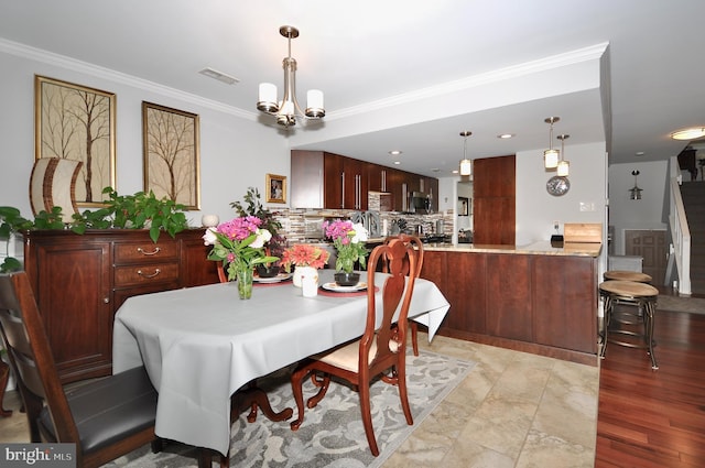 dining room with a chandelier, light hardwood / wood-style flooring, and crown molding