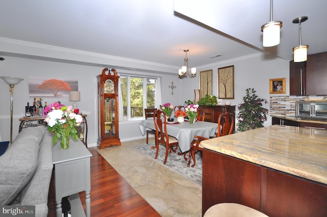 dining room featuring light wood-type flooring, ornamental molding, and a chandelier