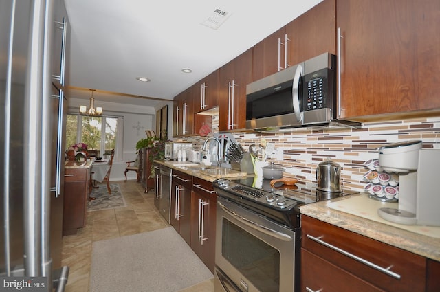 kitchen featuring sink, stainless steel appliances, a notable chandelier, backsplash, and pendant lighting