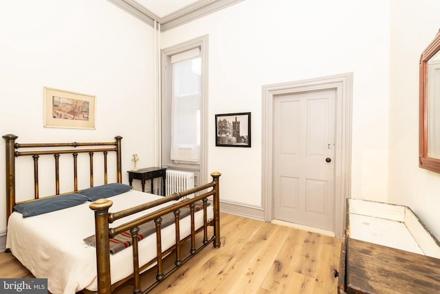 bedroom featuring light wood-type flooring, radiator, and ornamental molding