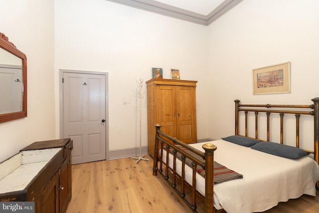 bedroom featuring light wood-type flooring, ornamental molding, and a towering ceiling