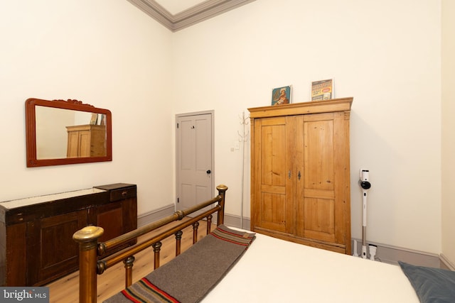 bedroom with light hardwood / wood-style floors, a towering ceiling, and crown molding