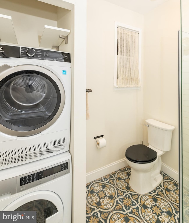 clothes washing area featuring tile patterned flooring and stacked washer and clothes dryer