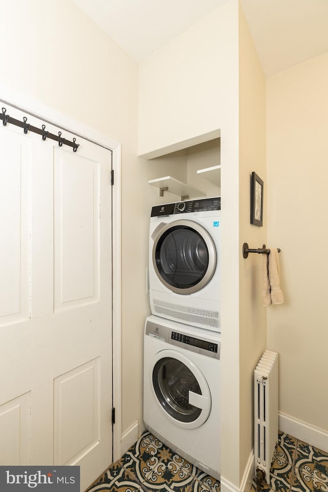 laundry area featuring radiator, light tile patterned floors, and stacked washing maching and dryer