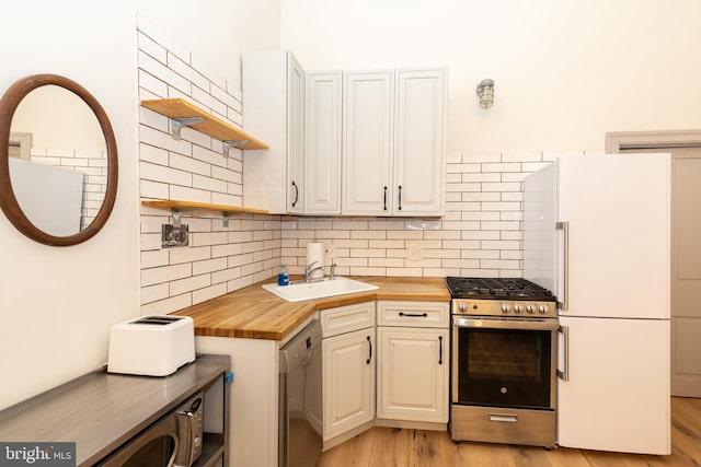 kitchen featuring wood counters, appliances with stainless steel finishes, tasteful backsplash, sink, and light hardwood / wood-style flooring