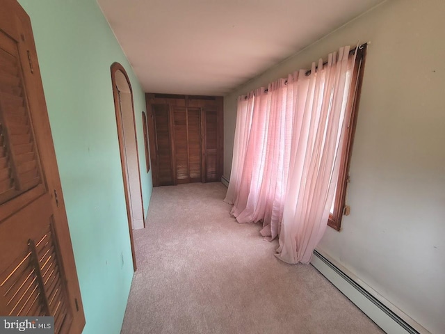 hallway with baseboard heating and light carpet