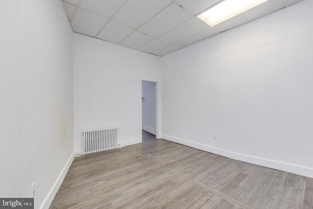 unfurnished room featuring hardwood / wood-style floors, a paneled ceiling, and radiator heating unit