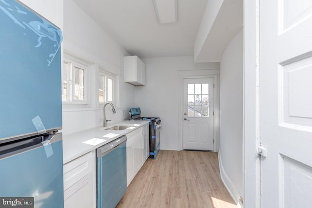 kitchen featuring white cabinets, light wood-type flooring, stainless steel appliances, and sink